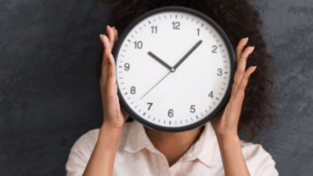 a woman holding a clock over her face - trusting the timing of your life